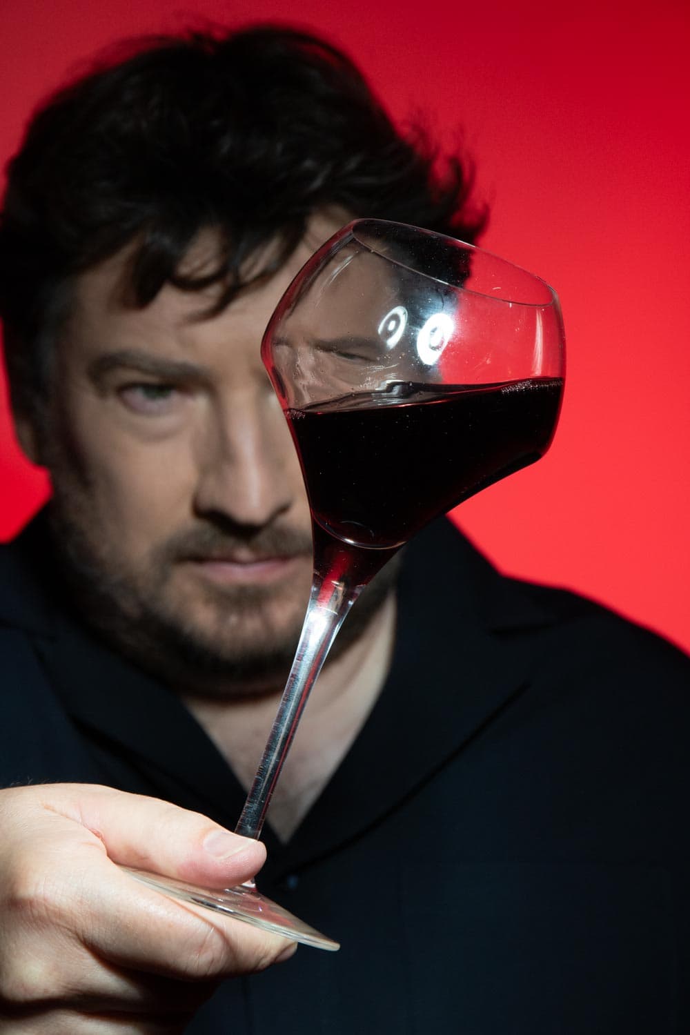 Dégustation de vin : verre de vin rouge observé à hauteur du regard sur fond rouge — Masterclass et Workshops